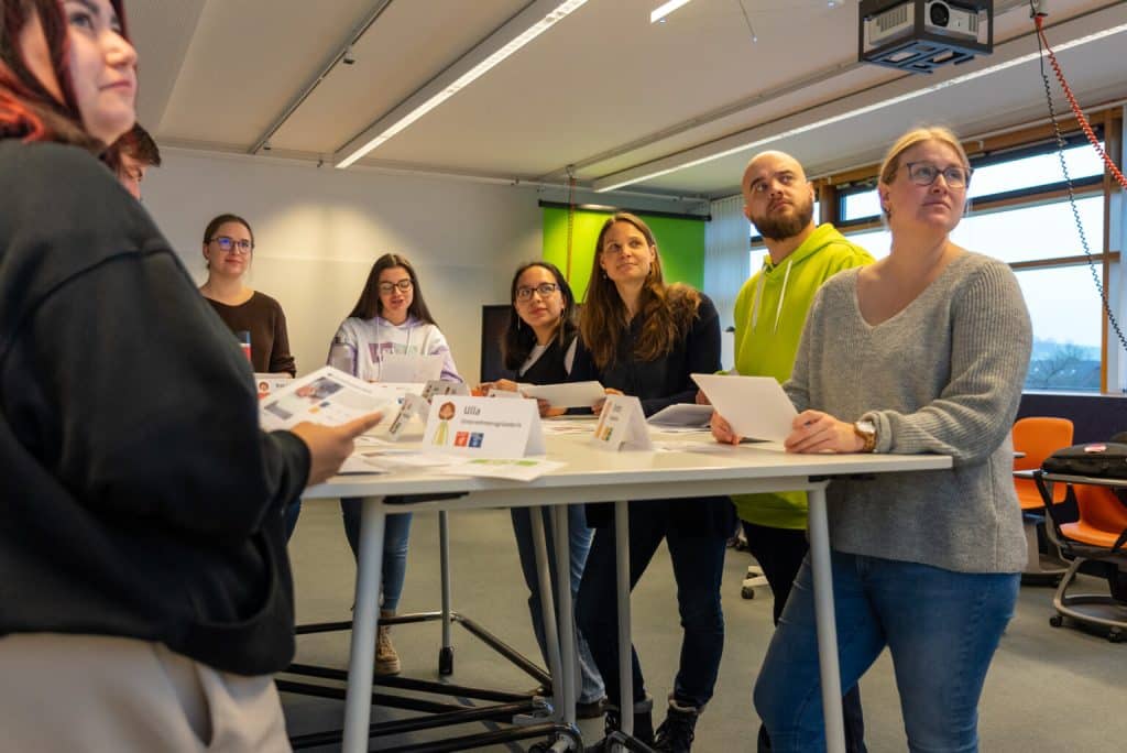 Eine Gruppe von Studierenden und Forschenden des Instituts für nachhaltige Wassersysteme der Hochschule Hof (inwa) diskutiert bei einer Besprechung. Das Bild zeigt die engagierte Zusammenarbeit und die Möglichkeiten für Karriere und akademische Abschlussarbeiten im Bereich nachhaltiger Wassersysteme.