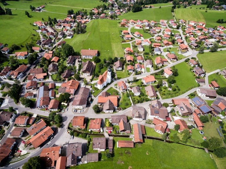 Eine Luftaufnahme einer ländlichen Gemeinde mit vielen Häusern, Straßen und grünen Flächen. Das Bild symbolisiert die wasserwirtschaftliche Analyse und Wegweisung für Kommunen durch das Institut für nachhaltige Wassersysteme der Hochschule Hof (inwa), um nachhaltige und effiziente Wassersysteme zu entwickeln.